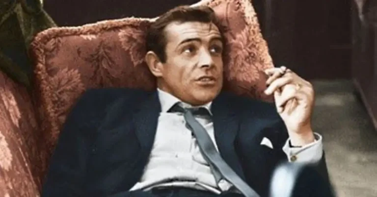 men in suit lying on sofa and is smoking a cigarette